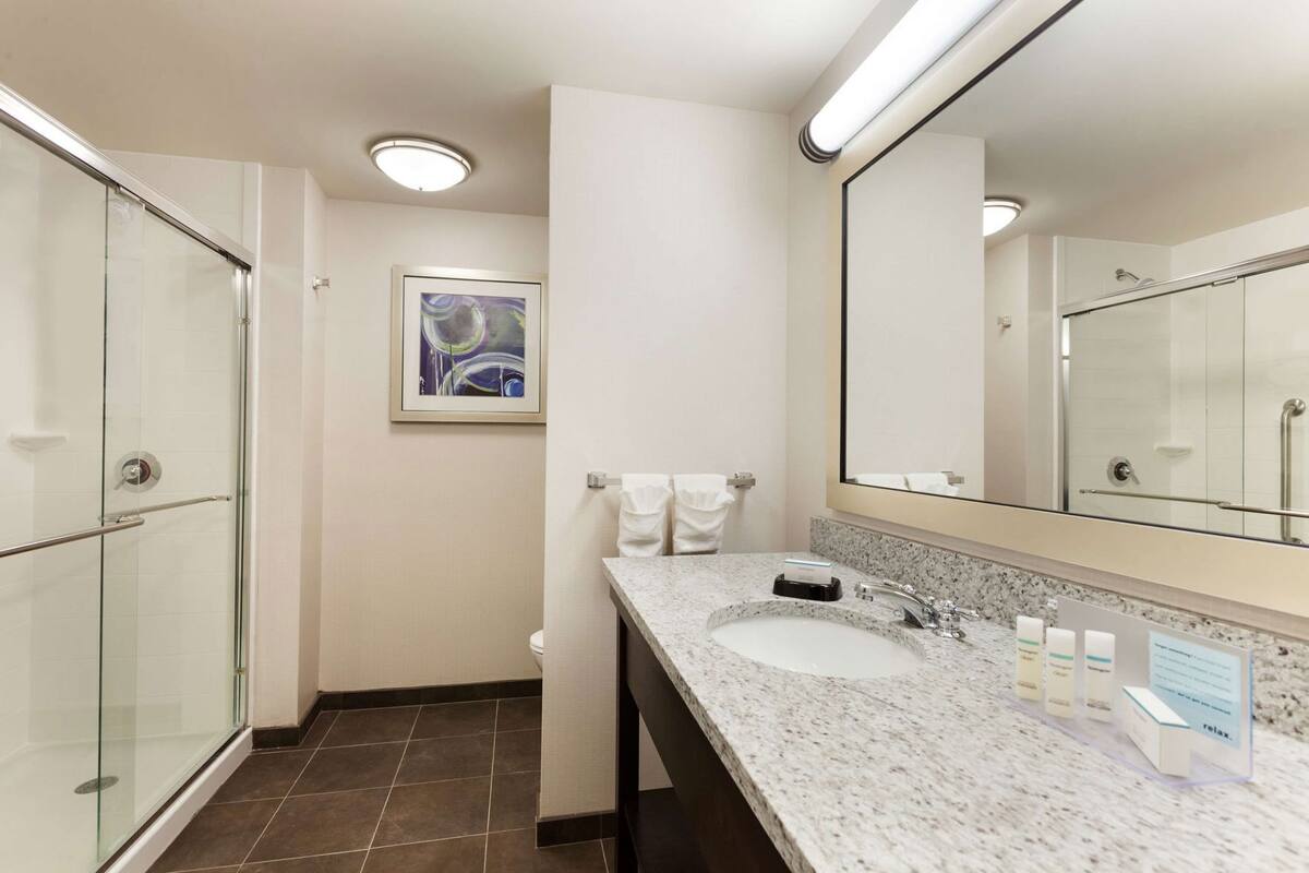 A modern bathroom with a glass shower enclosure, a marble sink, and a large mirror.