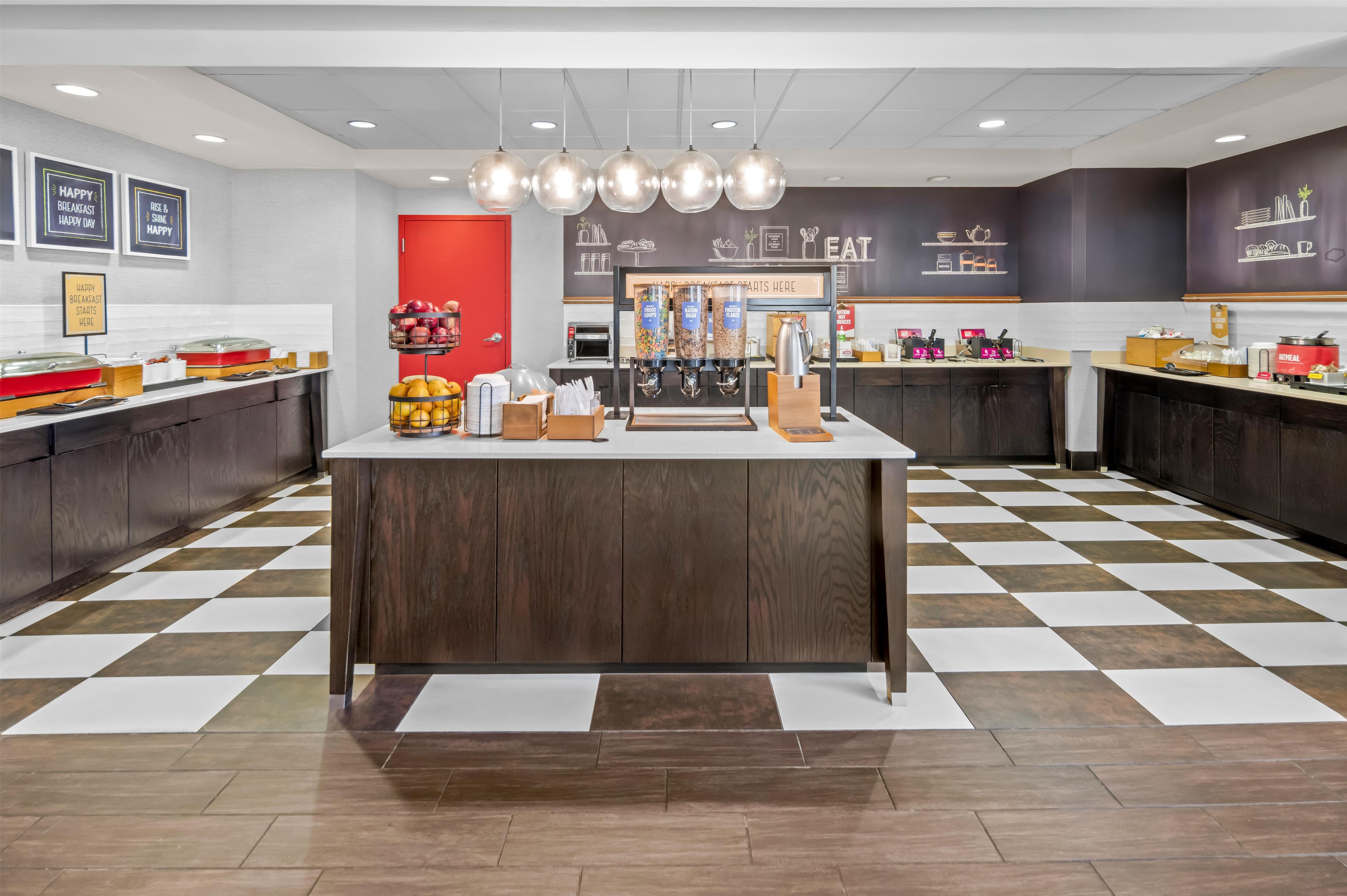 A modern breakfast bar with a checkered floor, a coffee machine, and a red door.