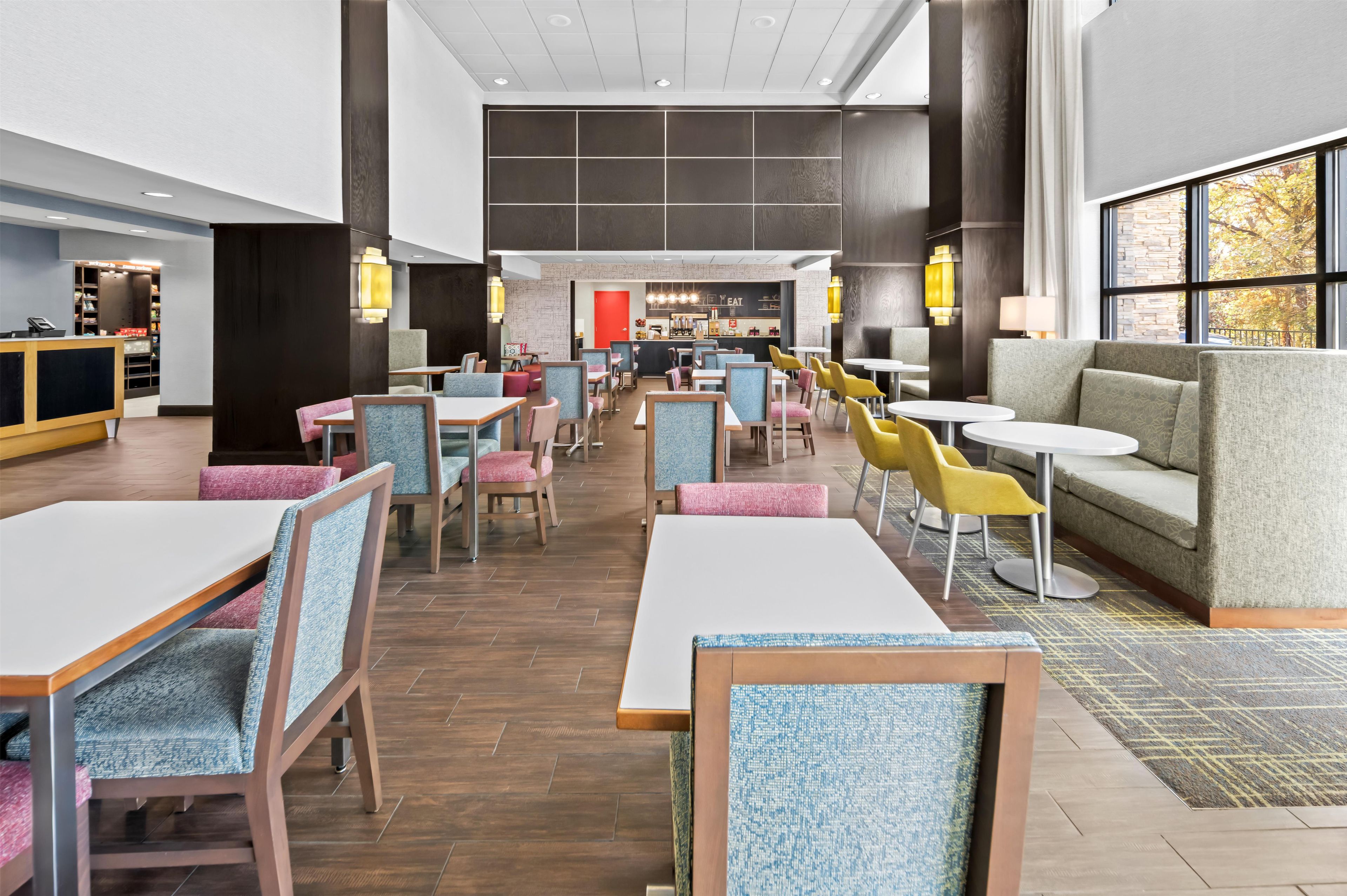 A modern hotel lobby with a long counter, seating areas, and a visible reception desk.