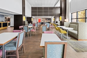 A modern hotel lobby with a long counter, seating areas, and a visible reception desk. - Hampton Inn & Suites Camp Springs/Andrews AFB (Suitland)