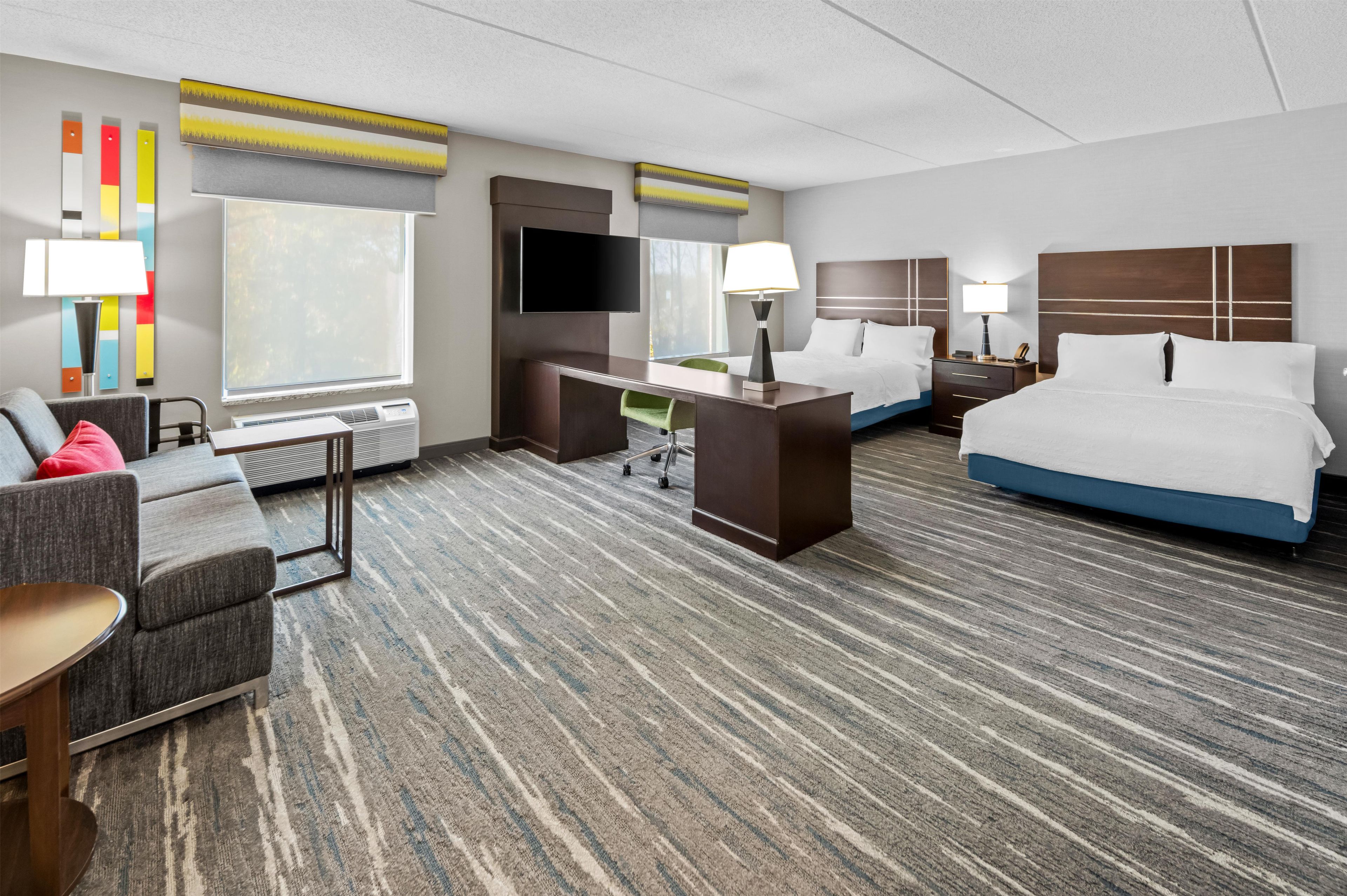Une chambre d’hôtel avec un lit, un bureau, une chaise, une télévision et une fenêtre.