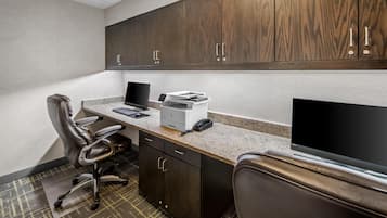 A modern office space with a desk, chair, computer, printer, and cabinets.