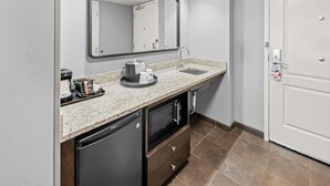 A bathroom with a sink, mirror, towel dispenser, and a trash bin. - Hampton Inn & Suites Camp Springs/Andrews AFB (Suitland)
