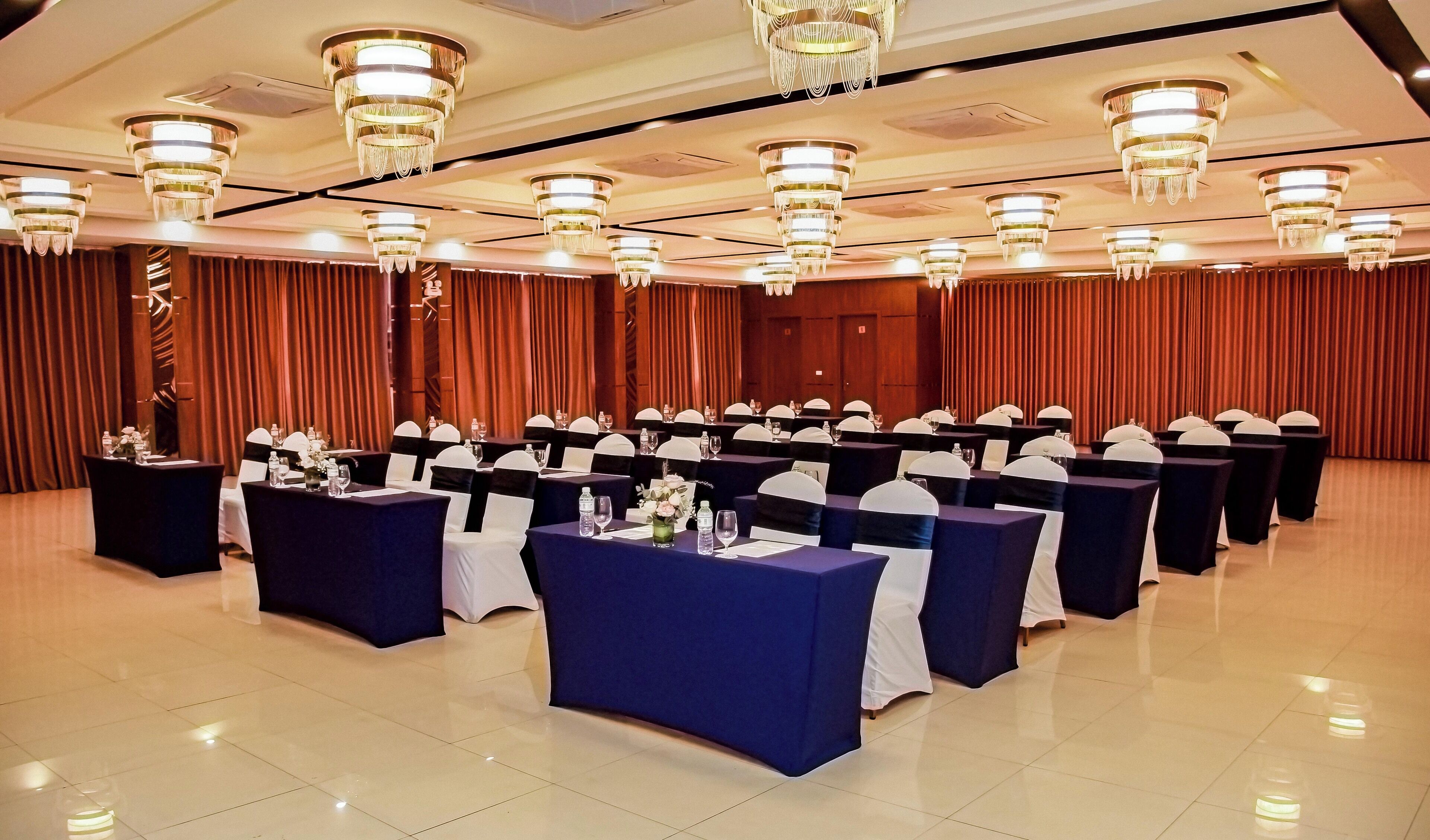 Un salón de conferencias con mesas, sillas y un escenario.