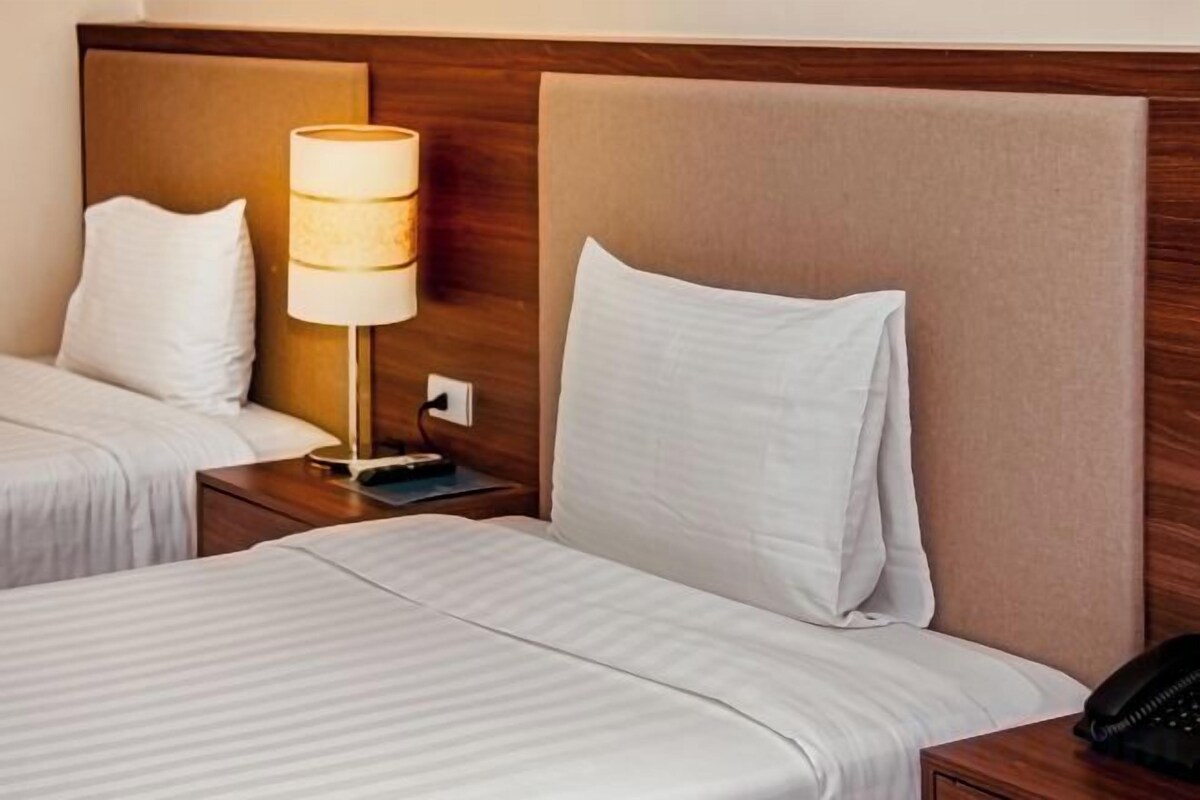 Habitación de hotel con dos camas, una lámpara de noche y un teléfono en la mesita de noche.