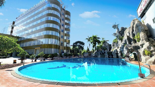 Ett hotell med en swimmingpool, en stor byggnad med en skylt och ett stenigt landskap med statyer.