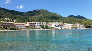 Une ville côtière aux eaux cristallines, bordée de bâtiments et dominée par un paysage montagneux.