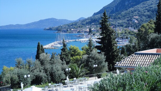 Une ville côtière dotée d’un port de plaisance, de bâtiments et bordée par une chaîne de montagnes.
