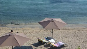 Une plage avec deux parasols et une chaise longue.