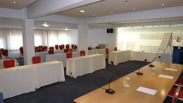 Ein Konferenzraum mit mehreren Tischen und Stühlen, ausgestattet mit Mikrofonen und Gläsern.