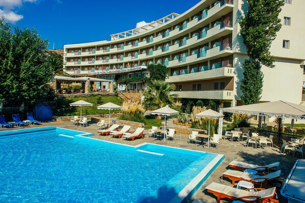 A hotel with a swimming pool, outdoor seating, and a landscaped garden. - Marmari Bay Hotel (Karystos)