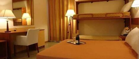 Habitación de hotel con literas, un escritorio, una silla, una lámpara y un espejo.