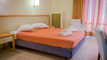 Una habitación de hotel con cama, escritorio, silla, espejo y ventana con cortinas.