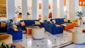 Eine großzügige Lobby mit blauen Sofas, gelben Sessel und weißen runden Tischen.