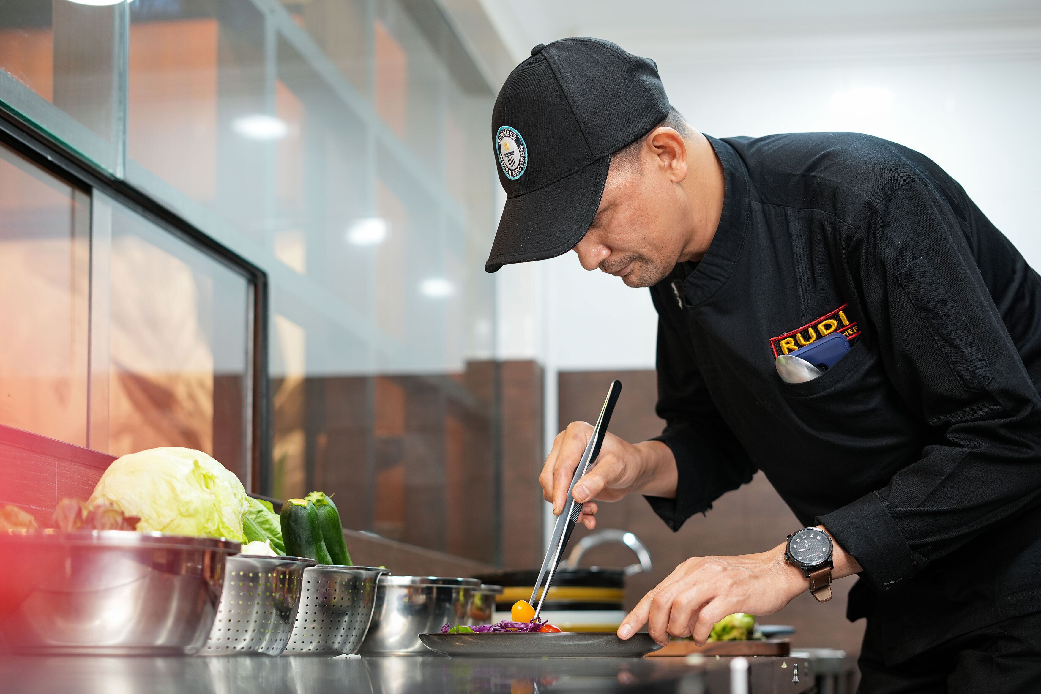 A chef preparing food in a kitchen with stainless steel appliances and a modern design.