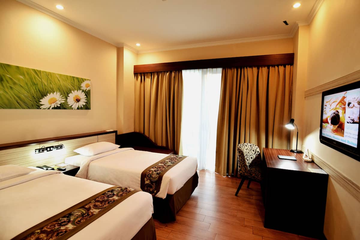 A hotel room with two beds, a desk, a chair, a television, and a painting on the wall.
