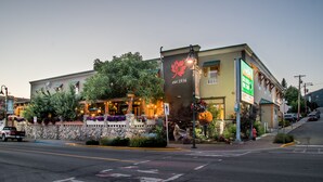 A building with a large sign reading "est. 1936" and a street view with parked cars and a pedestrian crossing.