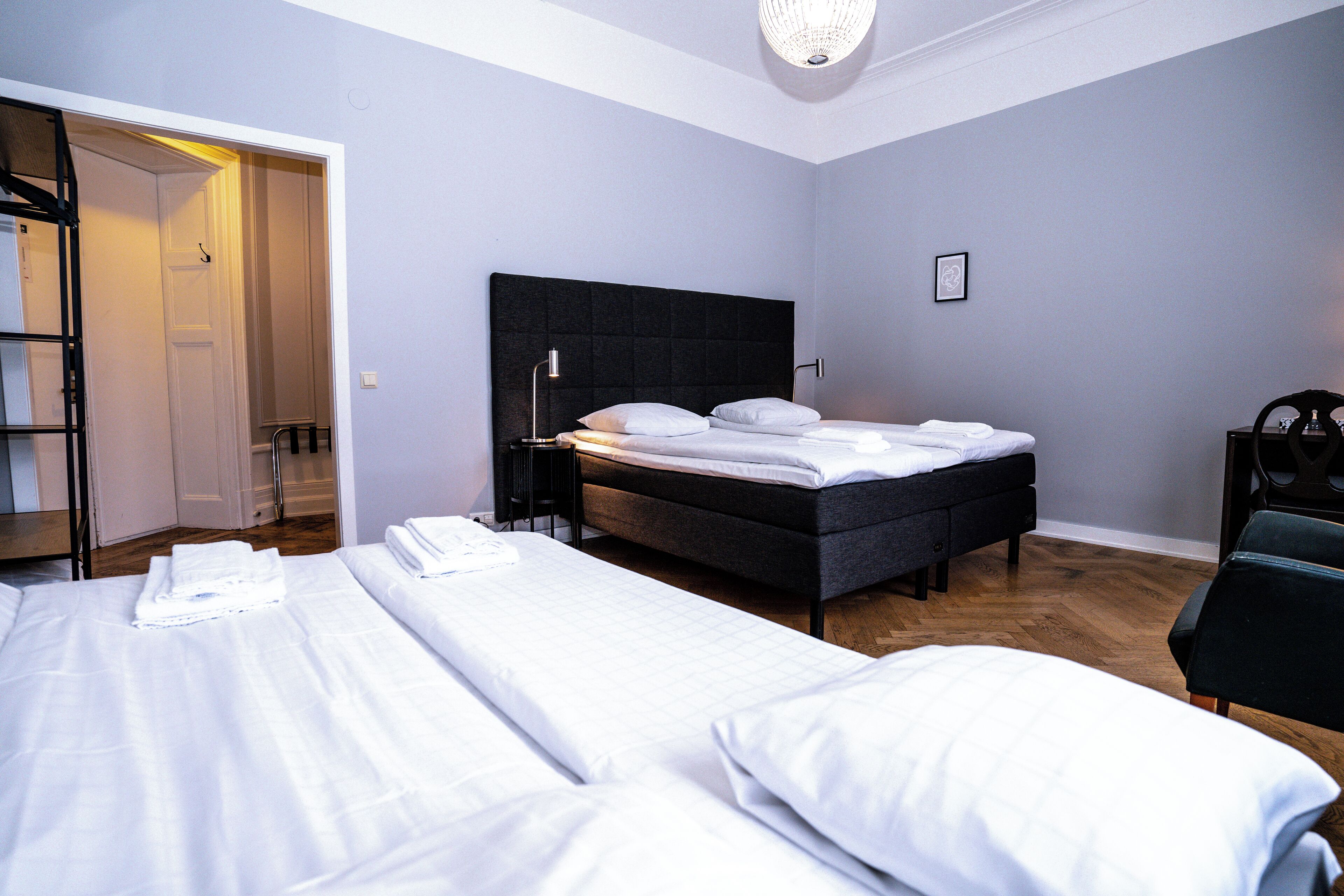A hotel room with two beds, a wardrobe, a desk, and a chair.