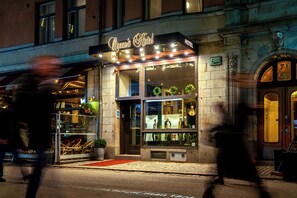 L’hôtel Queen’s, avec sa façade classique, ses grandes fenêtres et son entrée surmontée d’un tapis rouge.