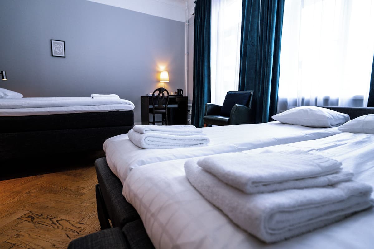 A hotel room with two beds, a desk, and a chair.