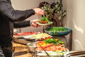 Un bufé con una variedad de alimentos, entre ellos verduras, carnes y quesos.
