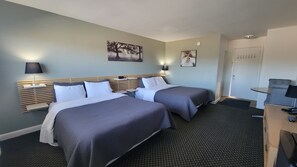 Habitación de hotel con dos camas, un escritorio y una silla.