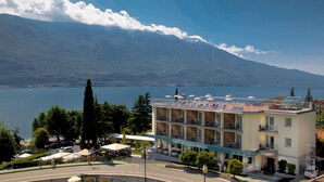 A hotel with a terrace overlooking a lake and mountains. - Hotel Sogno del Benaco (Limone sul Garda)