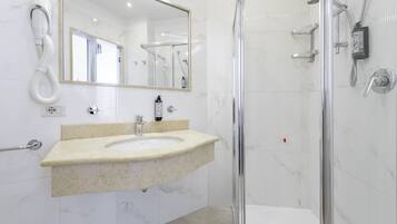 Un baño moderno con lavamanos de mármol, un espejo grande y cabina de ducha con paredes de vidrio.