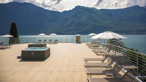 Terraza en la azotea con sillones de descanso y jacuzzis con vistas a un lago y montañas.