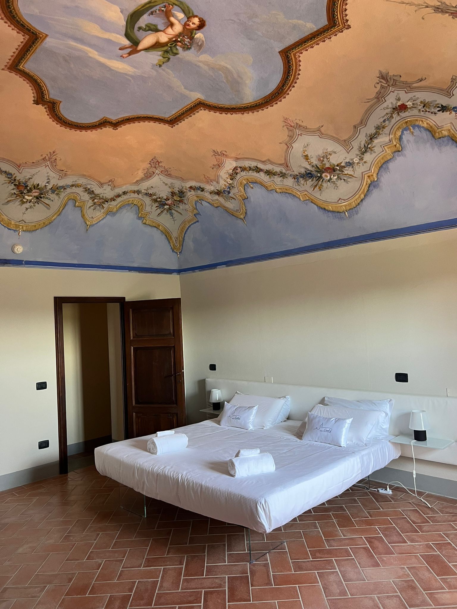 Une chambre d’hôtel avec un grand lit, une armoire en bois et un plafond décoré d’un putin.