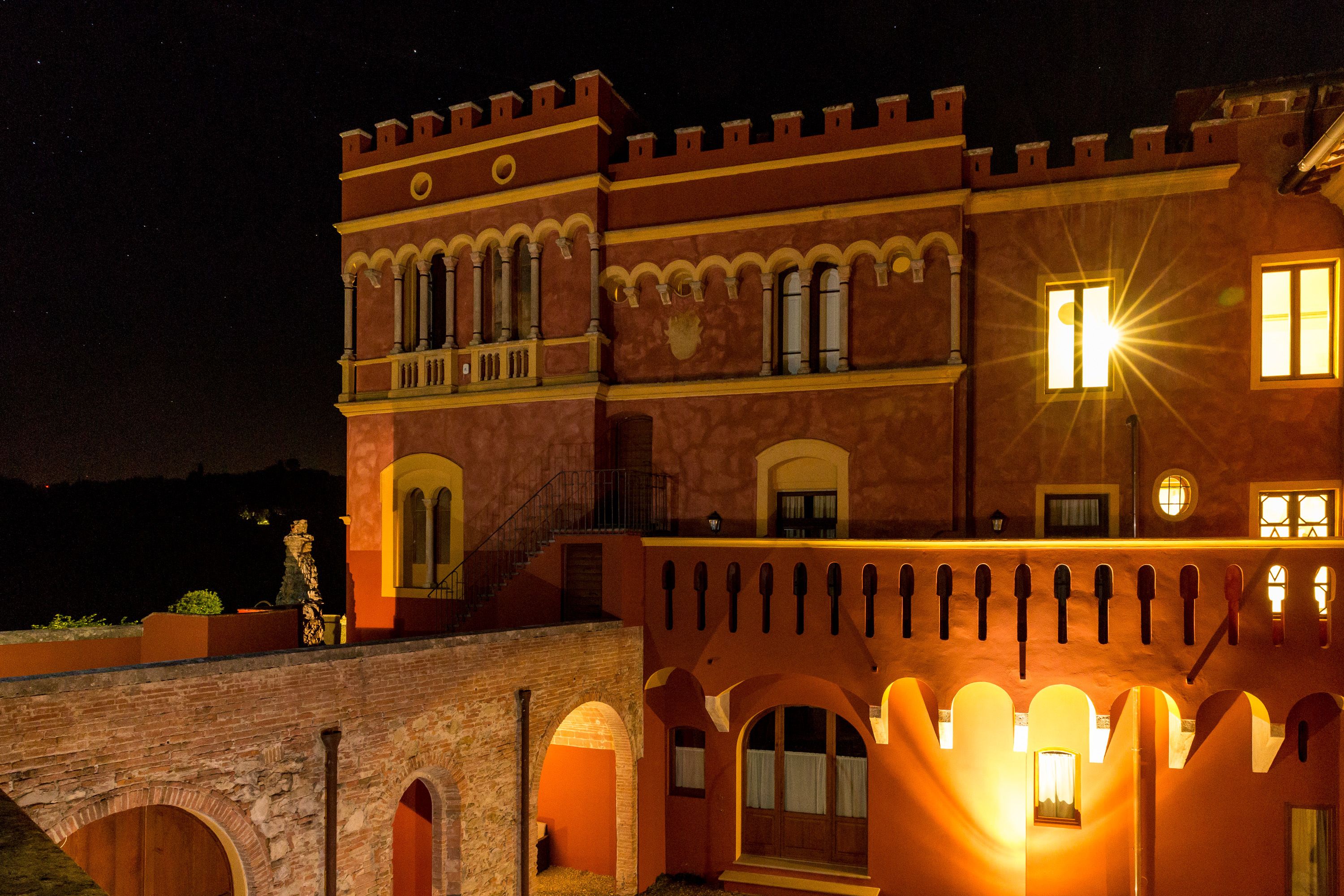 A historic building with arched windows and a balcony, illuminated at night.