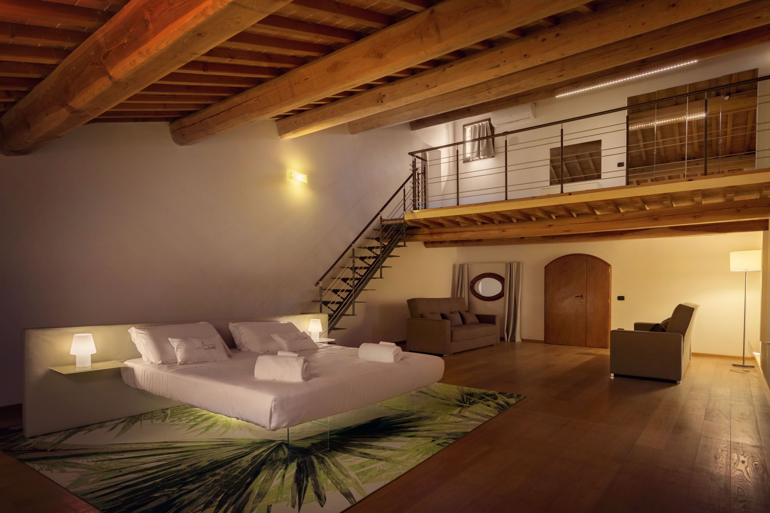 Een ruime kamer met een groot bed, een trap en een balkon.