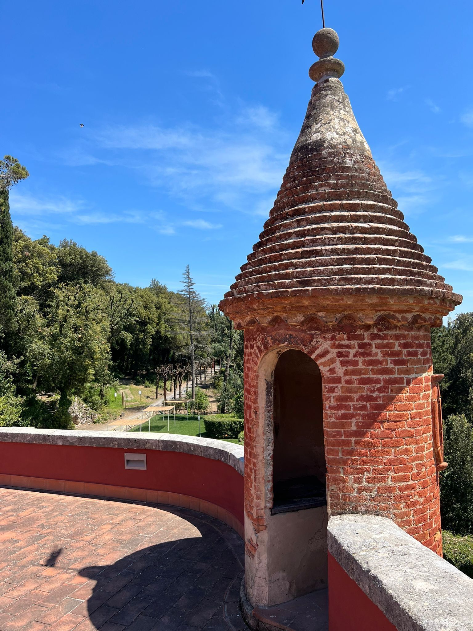 A brick structure with a conical roof, an arched entrance, and a small balcony.