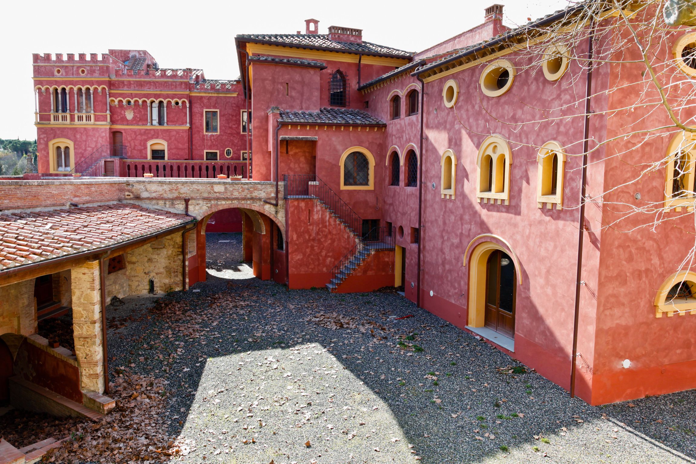A courtyard with a red building featuring arched windows and a tiled roof.