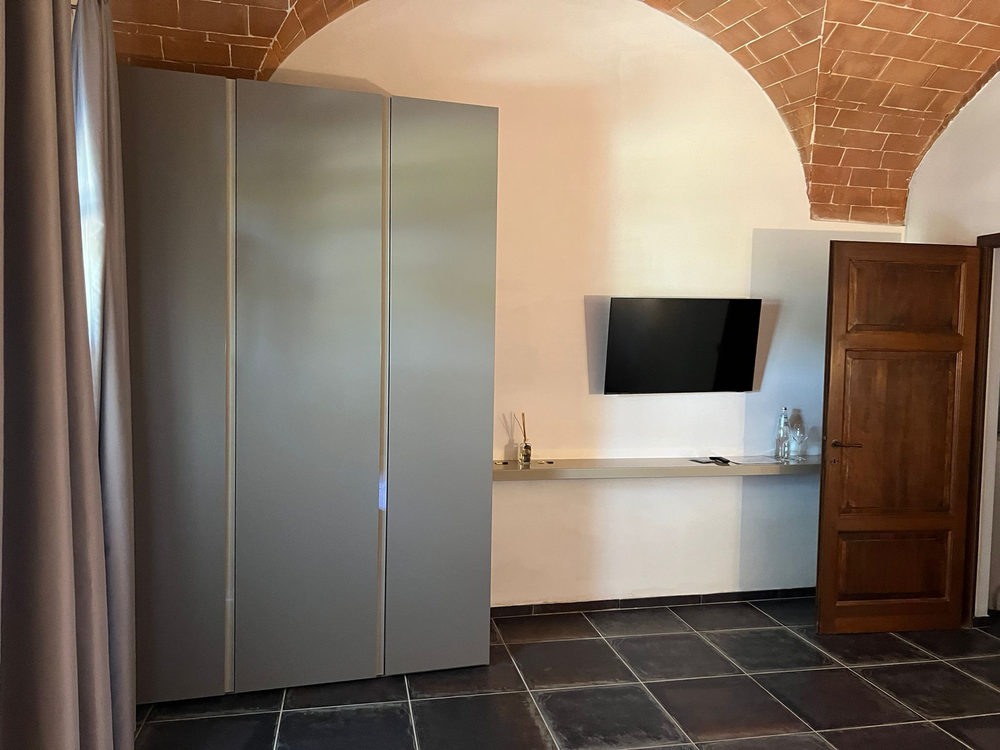 Una cocina moderna con un refrigerador empotrado, un televisor de pantalla plana montado en la pared y una puerta de madera.