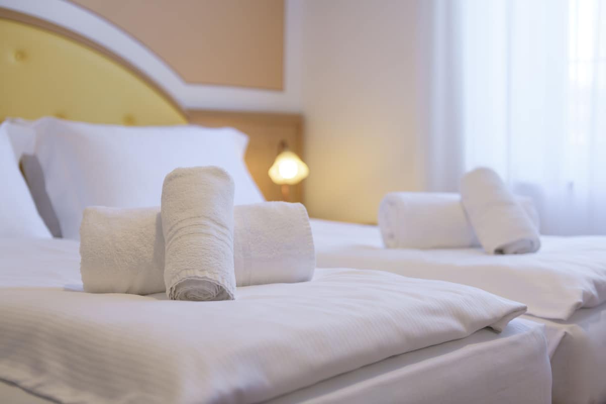 A hotel room with neatly made beds, white linens, and a headboard.