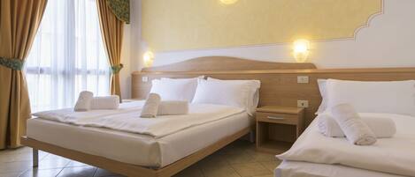 Habitación de hotel con dos camas, cabecero de madera, mesita de noche y lámpara de pared.