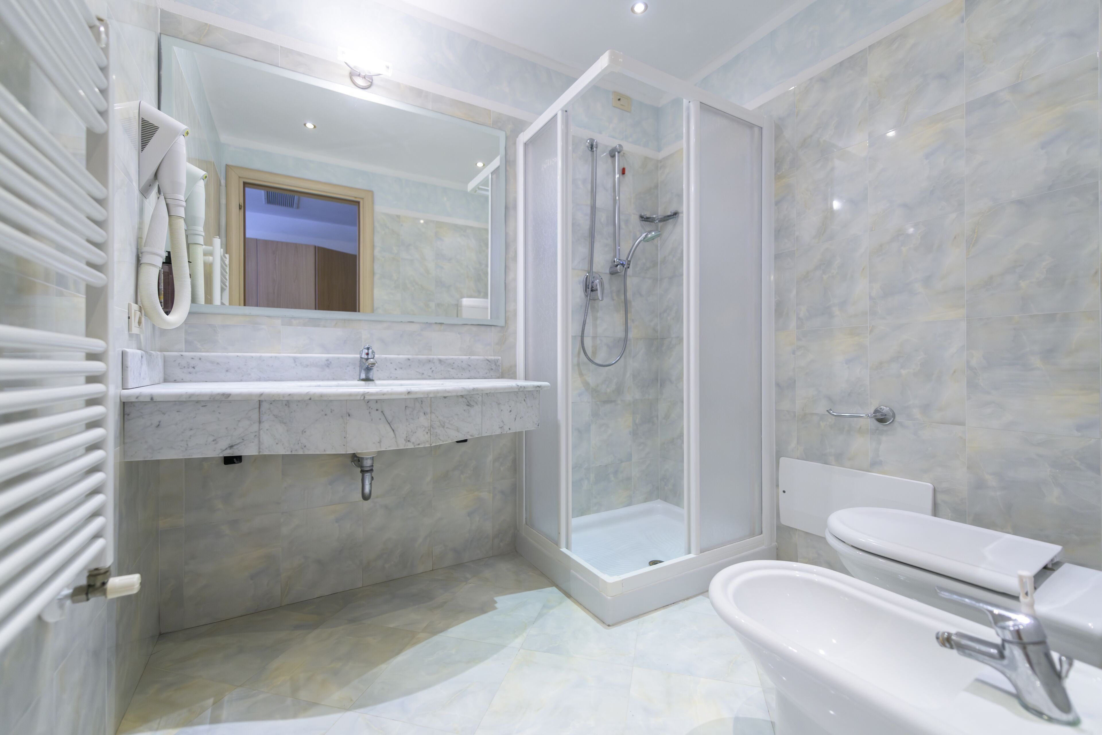 A modern bathroom with a shower, sink, and toilet.