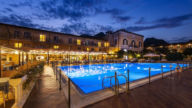 A poolside area with a swimming pool, outdoor seating, and a building with multiple balconies.