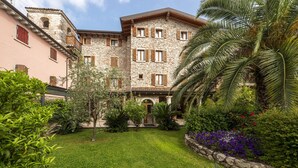 A stone building with multiple windows and a well-maintained garden with various plants and flowers.