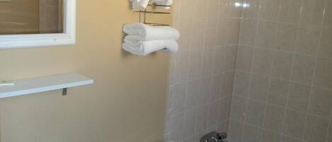 Un baño con inodoro, lavabo y bañera. Hay un perchero con toallas dobladas.