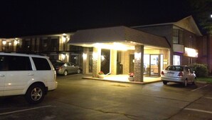A building with a covered entrance, a parking lot, and a few parked cars. - Oasis Motel (Niagara Falls)