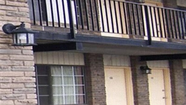 A multi-story building with a balcony on the second floor, featuring a metal railing and a lantern. - Oasis Motel (Niagara Falls)