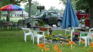 Un espace jardin avec des sièges extérieurs, une voiture et un panneau indiquant la présence d’un téléviseur.