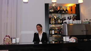 A bar area with a bartender, shelves of liquor, and a coffee machine. - Lungomare Hotel (Reggio Calabria)