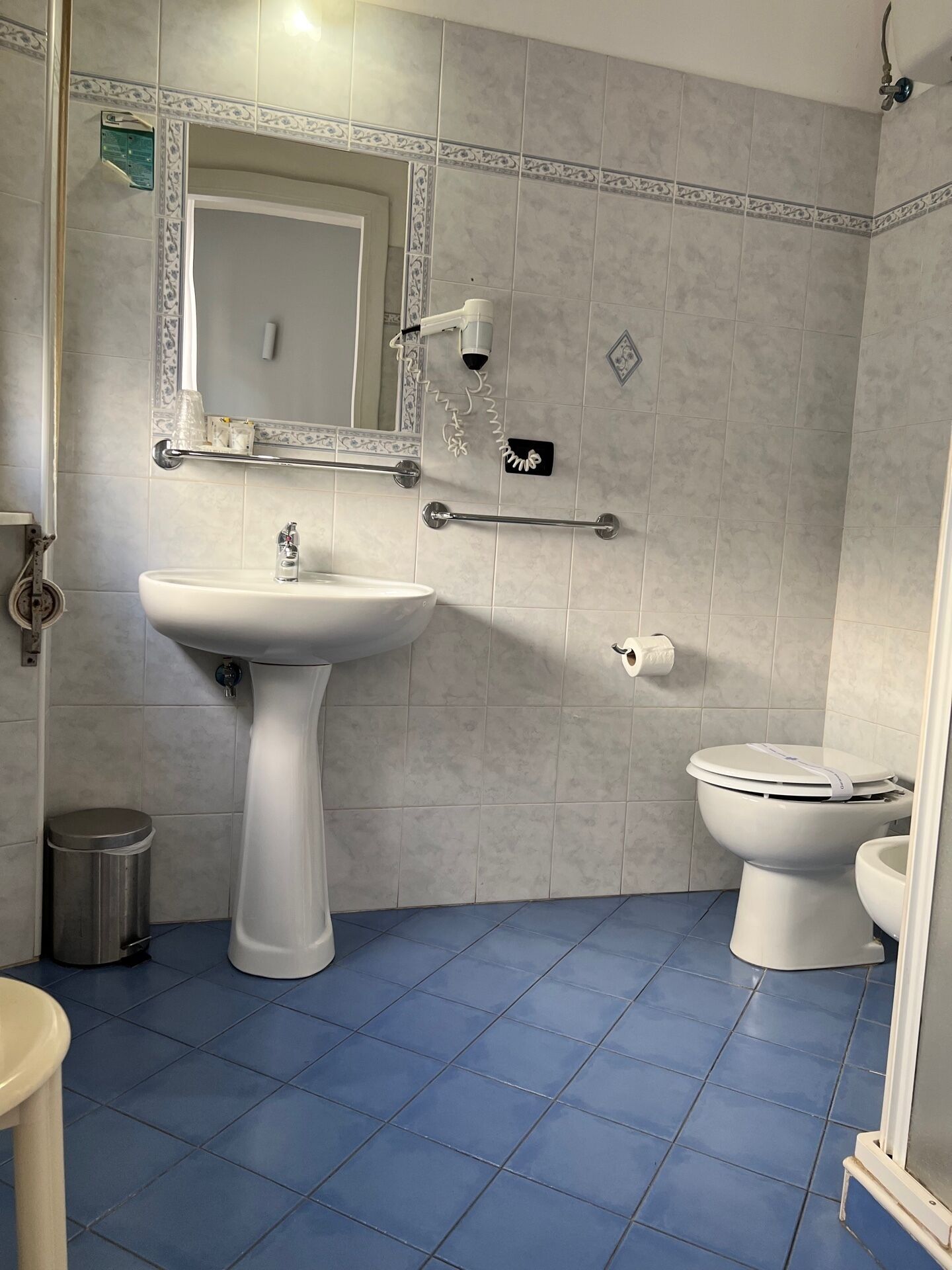 A bathroom with a pedestal sink, a toilet, and a mirror.