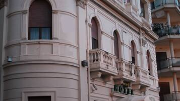 Un bâtiment historique, reconnaissable à son enseigne d’hôtel imposante, son architecture classique et son balcon orné d’une balustrade en fer forgé.