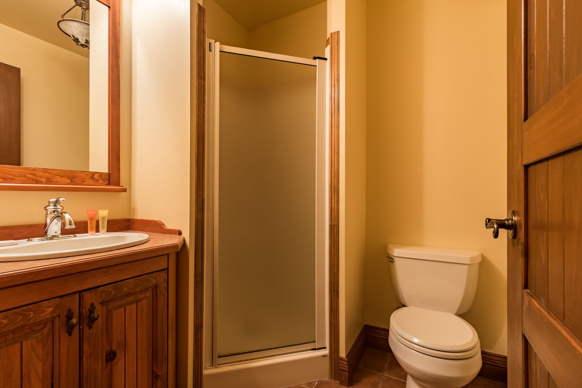 Et badeværelse med en trækommode, toilet og en glasbrusekabine.