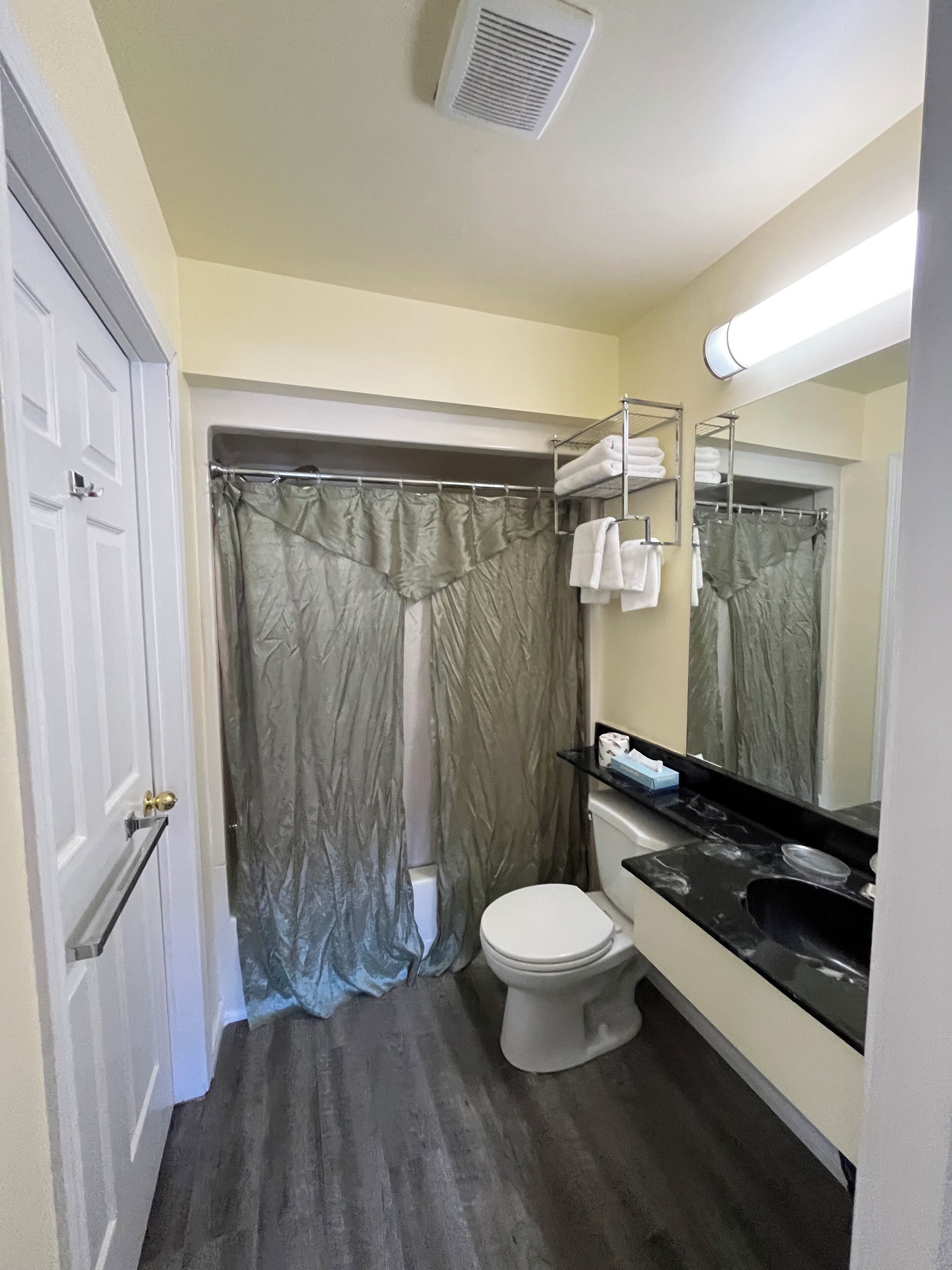A bathroom with a toilet, a sink, a shower curtain, and a towel rack.