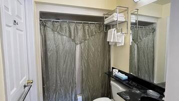 A bathroom with a toilet, a sink, a shower curtain, and a towel rack.